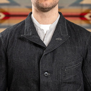 MotivMfg Peak Lapel Herringbone Denim Lounge Jacket Black close up collar worn