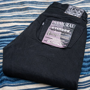 Eine schwarze Selvedge Jeans von Samurai auf blau-weißem Hintergrund. 